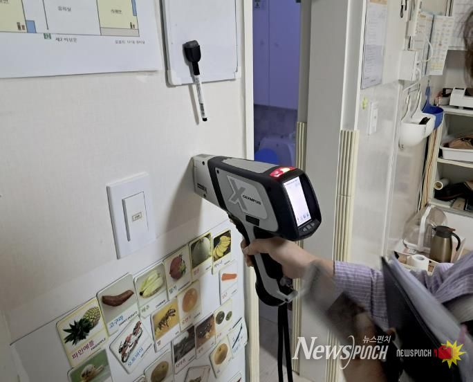 구청 관계자가 어린이집 실내 벽에 사용된 도료의 중금속 함량을 측정하고 있다