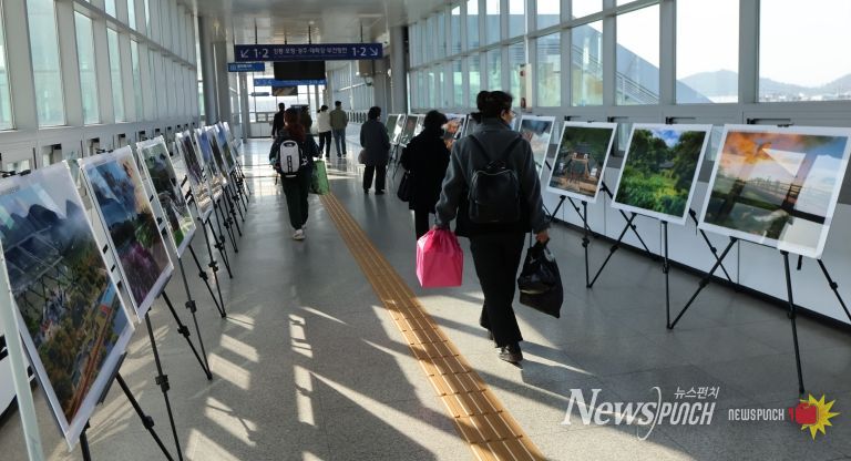 영천역 승강장 입출구 통로에 전시된 제17회 영천관광 전국사진공모전 입상작품을 철도 이용객들이 관람하고 있다.