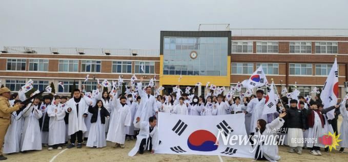 제5회 온양지역 3·11만세운동 재현행사에서 참가자들과 온양초 학생들이 대형 태극기와 함께 힘차게 만세를 외치며 기념촬영하고 있다.