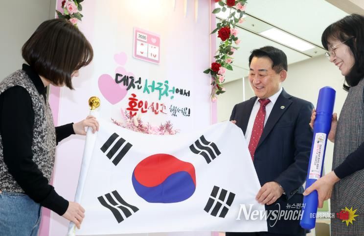 서철모 서구청장이 구청 민원실을 방문한 국제결혼 부부에게 태극기를 전하고 있다